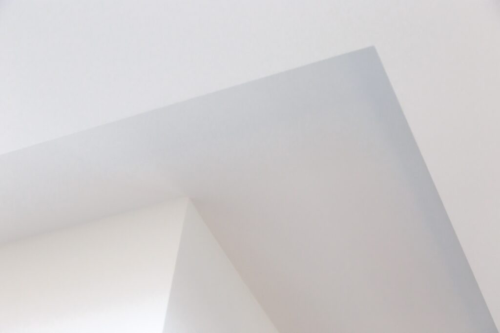 Bottom view of a wall corner and white plasterboard ceiling.